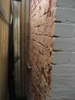 The colonial post shoe is buried below the tile surface allowing moisture in and trapping it, which is rusting the post shoe and cracking the tiles